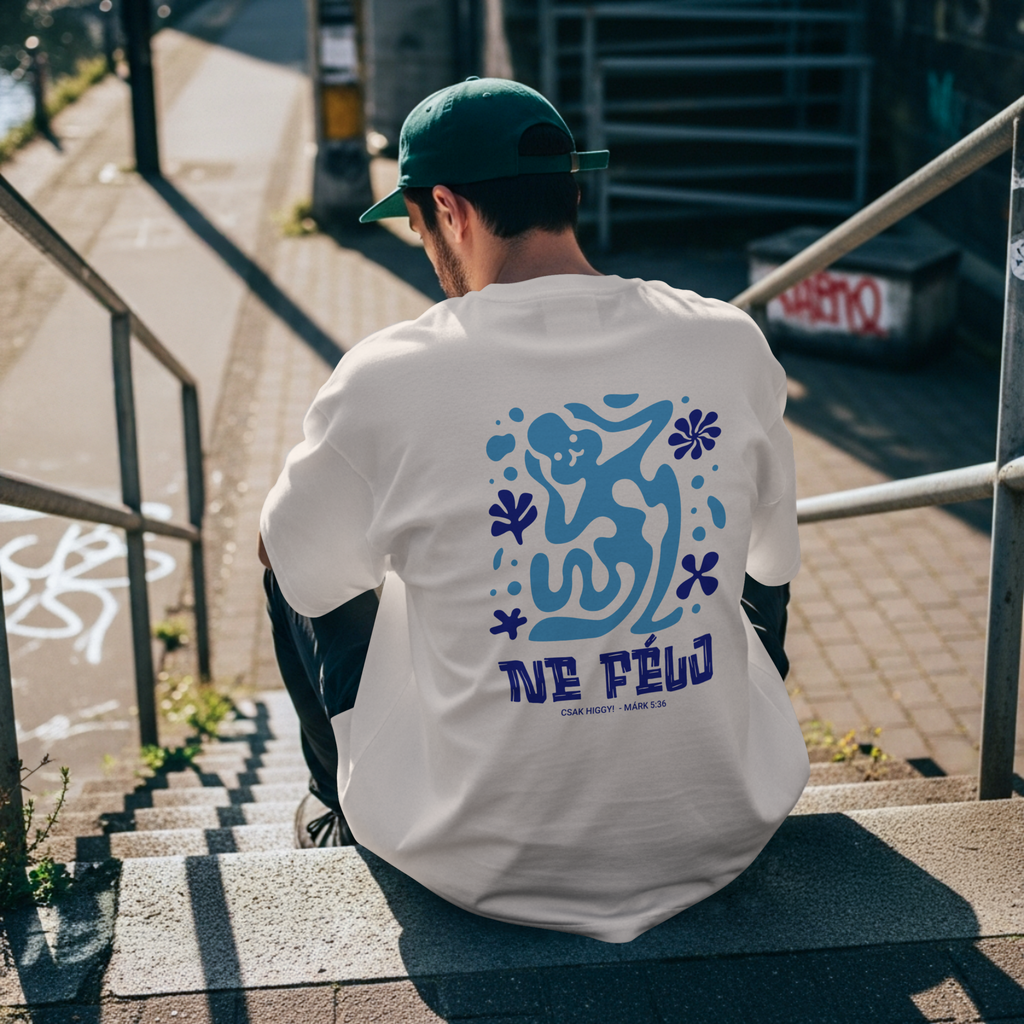 Person wearing a white t-shirt with blue graphics and text, sitting on stairs outdoors.